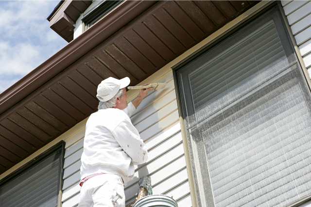 Exterior House Painter on a ladder painting the side of a home