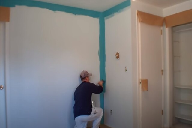 Worker painting inside the house with a roller and a paint of can