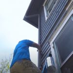 Worker painting outside of the house on a ladder