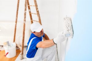 Residential painter with a ladder painting a wall with a roller